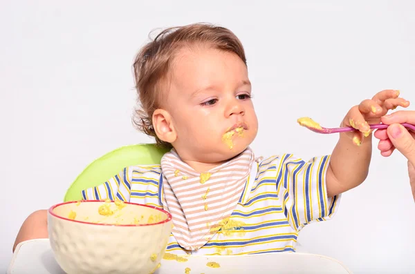 Bebê comendo comida com uma colher, criança comendo bagunçado e ficando — Fotografia de Stock