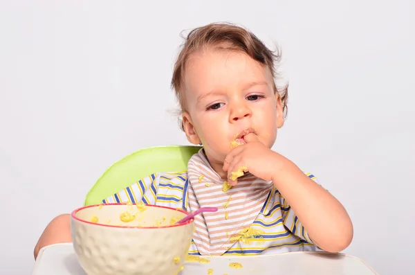 Bebé comiendo comida con una cuchara, niño pequeño comiendo desordenado y recibiendo —  Fotos de Stock