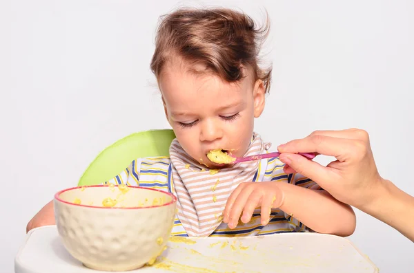 Baby eating food with a spoon, toddler eating messy and getting — Stockfoto