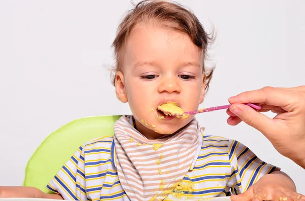 Bambino mangiare cibo con un cucchiaio, bambino mangiare disordinato e ottenere — Foto Stock