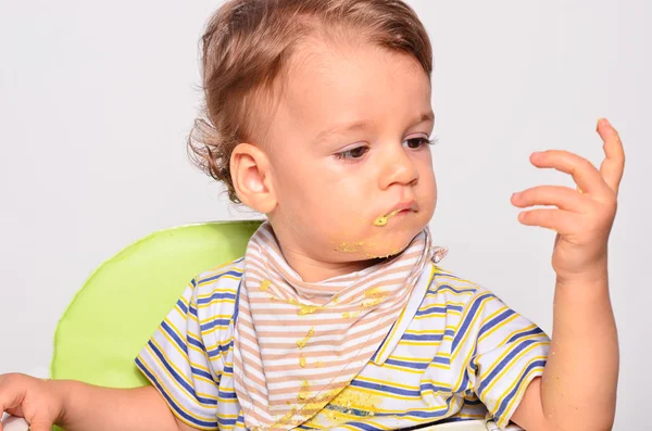 Baby eating food with a spoon, toddler eating messy and getting — Zdjęcie stockowe