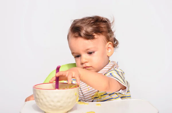 Baby eating food with a spoon, toddler eating messy and getting Royalty Free Εικόνες Αρχείου