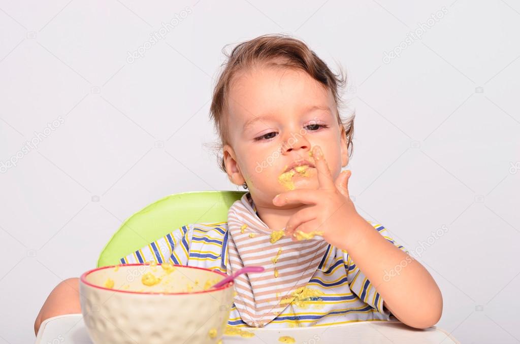 Baby eating food with a spoon, toddler eating messy and getting