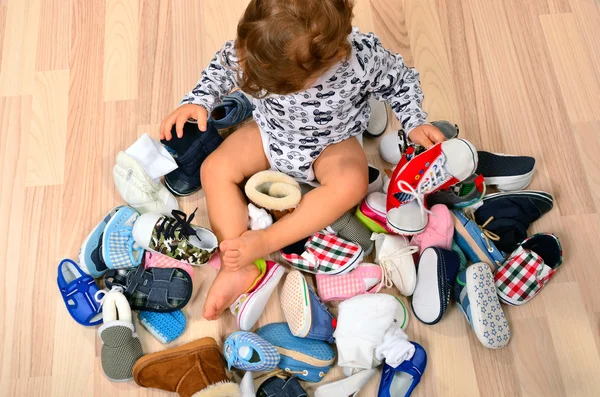 Мальчик, играющий с большим количеством детской обуви . — стоковое фото