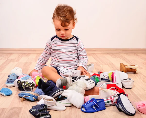 Tout-petit jouant avec beaucoup de chaussures de bébé . — Photo