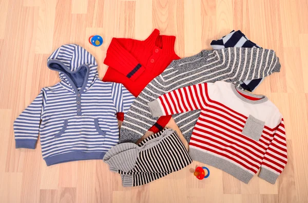 Baby clothes lying on the floor. Winter child sweaters arranged. — Stock Photo, Image