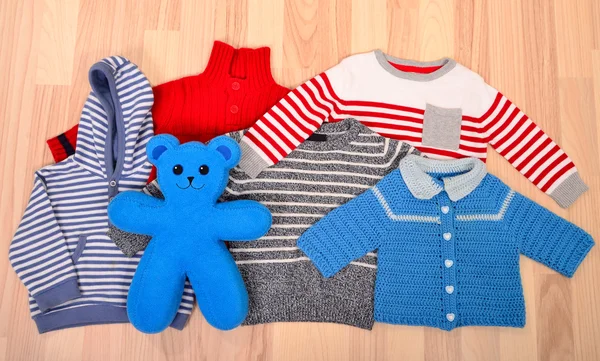 Dětské oblečení ležící na podlaze. Zimní dětské svetry uspořádány. Stock Fotografie