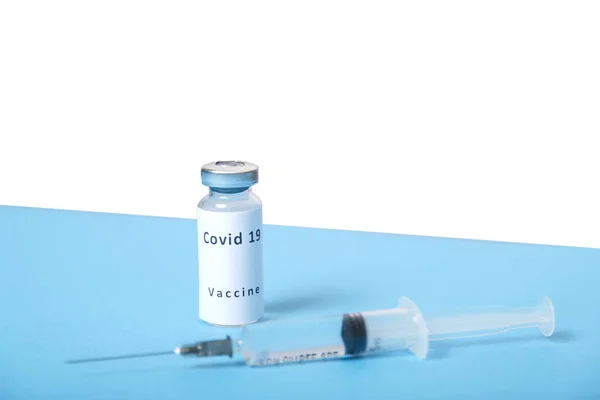 Шприц і флакон з вірусною вакциною на синьому столі, вид зверху . — стокове фото