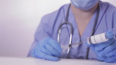 Eldivenli bir doktor şırıngayı virüse karşı aşıyla dolduruyor.