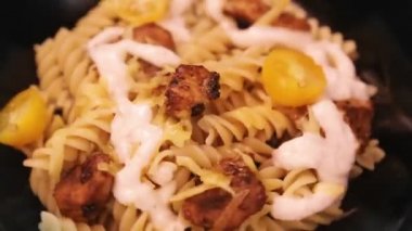 Siyah tabakta tavuk ve peynirli makarna daire şeklinde döner.