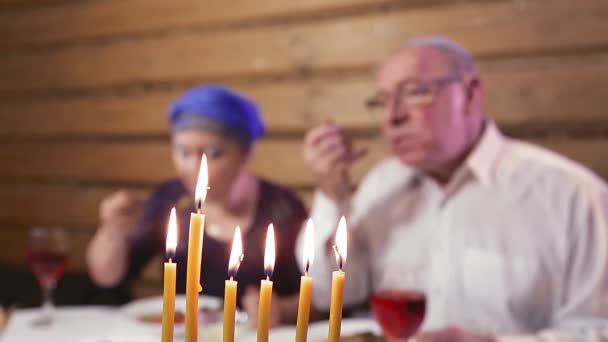 Judisk gift par i traditionella huvudbonader vid festbordet i dagarna av Hanukkah ljus i förgrunden av ansiktet i oskärpa. — Stockvideo