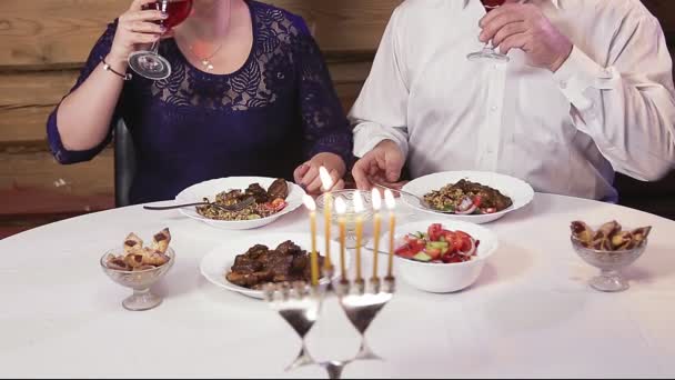 在光明节的日子里，一对犹太夫妇在一张喜庆的餐桌前，没有面孔 — 图库视频影像
