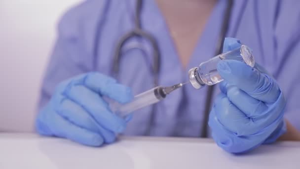 Un médico con guantes llena una jeringa con una vacuna contra el virus — Vídeo de stock