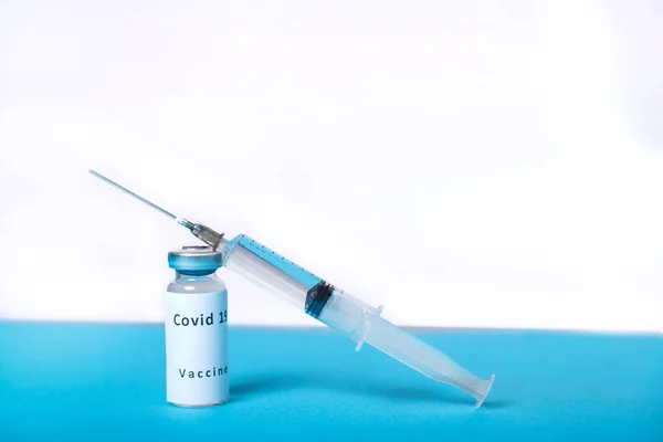 Вірусна вакцина і шприц на столі на синьо-білому тлі . — стокове фото