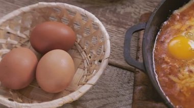 Kızartma tavası ve Shakshuka ahşap bir standın üzerindeki masada.