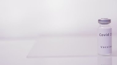 Beyaz bir zemin üzerinde virüs aşısı olan bir şişe.