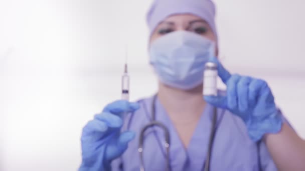 Un médecin en gants et un masque prennent un vaccin contre le virus et une seringue dans ses mains. — Video