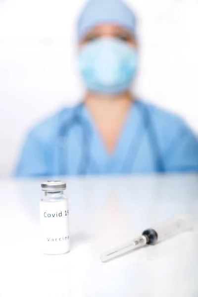 Op de tafel ligt een vaccin preventie van het virus en een spuit op de achtergrond een arts in vervaging. — Stockfoto