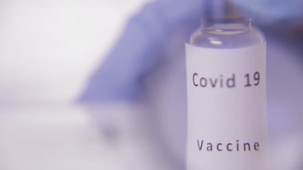 ウイルスと注射器に対するワクチンの瓶は虫眼鏡を通して検査されます — ストック動画