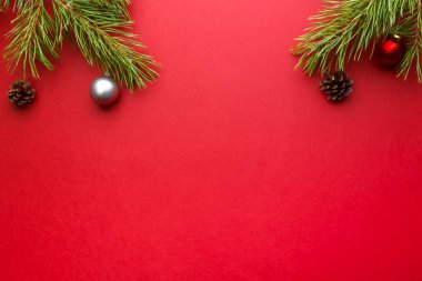 Kırmızı arka planda bir çam dalında Noel çerçevesi süslemeleri ve yazıtlar için bir yer.