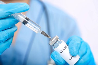 Eldivenli bir doktor şırıngayı virüsü önlemek için aşıyla dolduruyor..