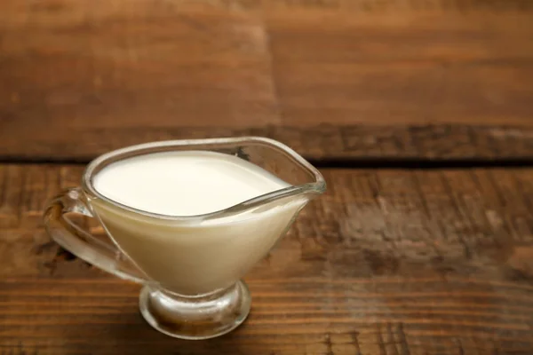 Tahta masadaki sos için bir sürahi şeffaf krema..