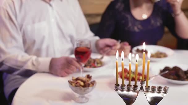 Una pareja judía casada en una mesa festiva en los días de Janucá sin rostros. — Vídeo de stock