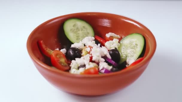 Греческий салат в бежевой тарелке на белой пластине вращается по кругу. — стоковое видео