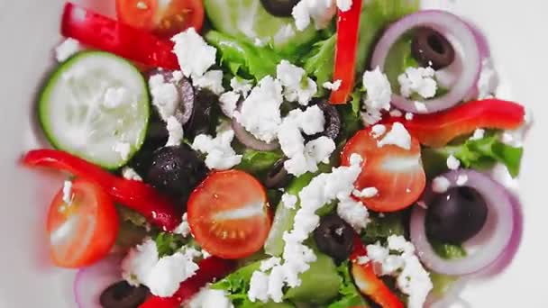 Грецький салат на білій пластині обертається по колу. — стокове відео