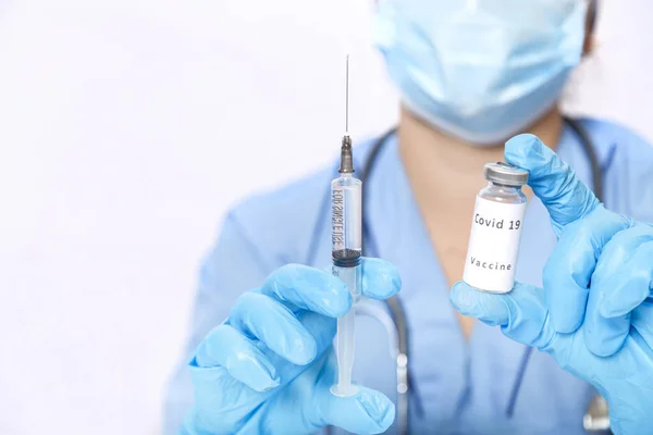 Een injectieflacon met een vaccin ter voorkoming van een virus in de handen van een arts en een spuit. — Stockfoto