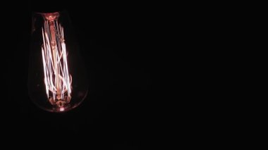 Tungsten spiral lambasıyla yanan lamba siyah arka planda yanıp sönüyor. Boşluğu kopyala.
