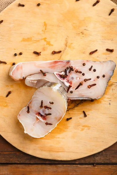 新鲜的白色鳕鱼在旁边撒满调味品的木板上蒸着 — 图库照片
