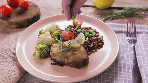 Vrouwelijke handhagelslag gebakken vis met linzen met groene uien in een beige bord. — Stockvideo