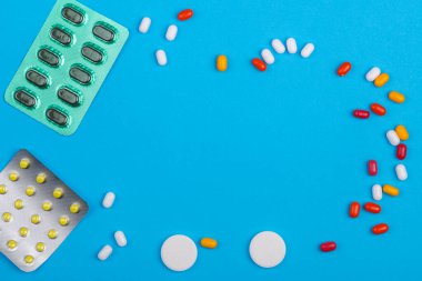 Kabarcıklardaki ilaç ve haplar mavi arka plan fotokopi alanına saçılmış. Yatay fotoğraf