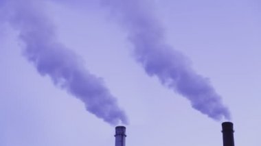 Gece kızıl gökyüzünün arka planında buhar çıkan bir boruyla ısı santrali. Genel plan