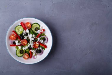 Beyaz tabak, gri beton arka planda Yunan salatası. Uzayı kopyala Yatay fotoğraf
