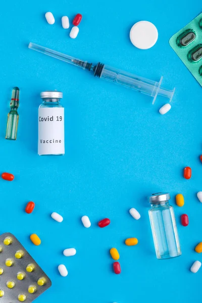 散乱テープ 青い背景に薬アンプルと注射器と水疱 垂直写真 — ストック写真