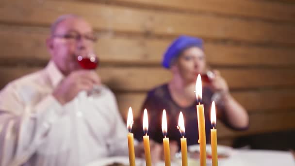 Pasangan menikah Yahudi dalam hiasan kepala tradisional di meja perayaan pada hari-hari lilin Hanukkah di bagian depan wajah kabur — Stok Video