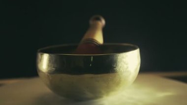 Siyah arka planda tokmağı olan şarkı söyleyen bir kase daire şeklinde döner..