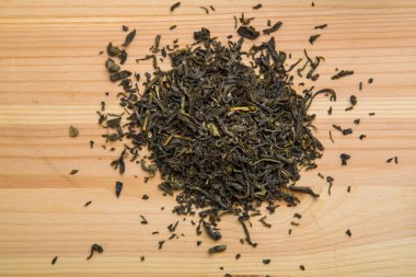 Tahta bir masanın üzerinde, çay yaprakları masaya saçılmış..