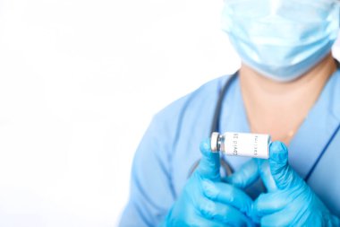 Maskeli bir doktorun elinde virüse karşı aşı olan bir şişe..
