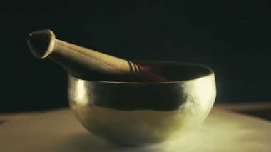 Siyah arka planda tokmağı olan şarkı söyleyen bir kase daire şeklinde döner.