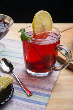 Kaşık, limon, limon ve vazo ve peçetenin yanında çilek çayı..