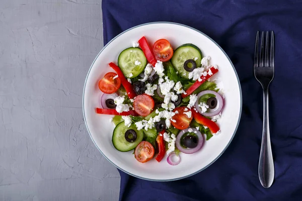 Placa ligera de ensalada griega sobre una servilleta azul sobre un fondo de hormigón. — Foto de Stock