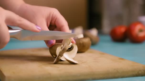 Female hand on a wooden board cuts champignons with a knife — Stock Video