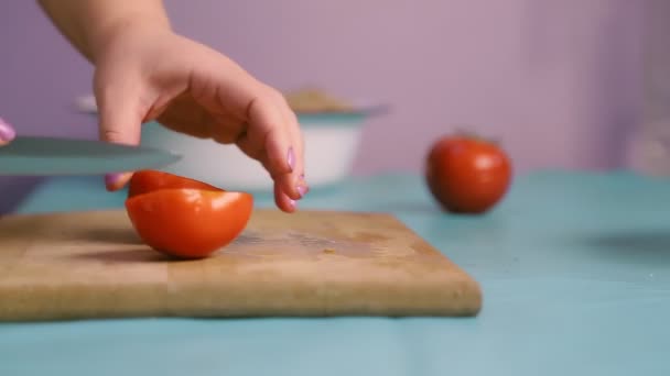 Ένα γυναικείο χέρι σε μια ξύλινη σανίδα κόβει ντομάτες με μαχαίρι — Αρχείο Βίντεο