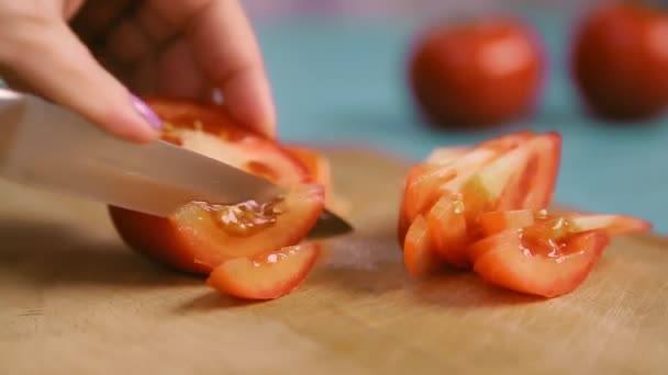 Жіноча рука на дерев'яній дошці розрізає помідори ножем — стокове відео
