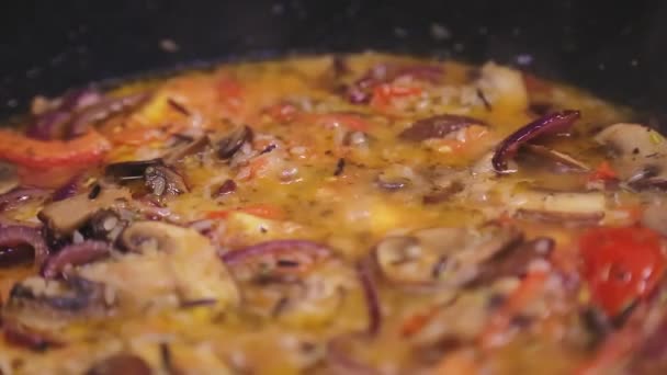 Risotto with mushrooms and tomatoes boils over the fire. — Stock Video