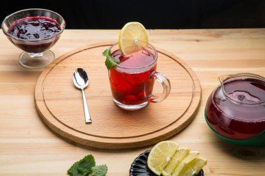 Çay fincanının içinde çay demlik kaşığının yanında limon ve limon merhemi. Yuvarlak bir tezgahın üstünde..