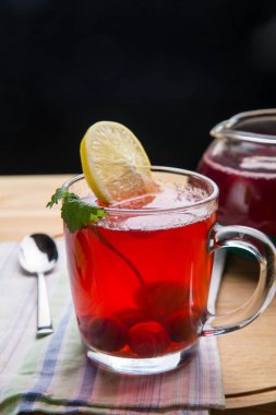 Limonlu bardakta çilek çayı peçetenin üstünde kaşığın yanında..